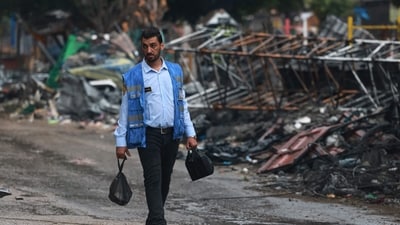 Israel-Hamas War: A Palestinian man wearing a United Nations blue vest walks past the debris following the Israeli bombardment of Rafah in the southern Gaza Strip. (AFP) Israel-Hamas War: A Palestinian man wearing a United Nations blue vest walks past the debris following the Israeli bombardment of Rafah in the southern Gaza Strip. (AFP)