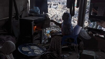 Israel-Hamas War: A Palestinian woman bakes bread in her home destroyed during the Israeli bombardment of Gaza, in Bureij. (AFP) Israel-Hamas War: A Palestinian woman bakes bread in her home destroyed during the Israeli bombardment of Gaza, in Bureij. (AFP)
