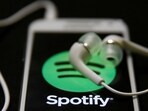 Earphones are seen on top of a smart phone with a Spotify logo on it,