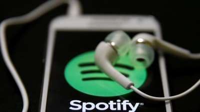 Earphones are seen on top of a smart phone with a Spotify logo on it, (REUTERS)
