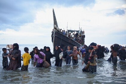 Rohingya Muslims walk through waters after they are temporarily allowed by locals to land in Ulee Madon beach, North Aceh, Indonesia, November 16, 2023. (Reuters)
