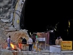 Members of rescue teams stand at the entrance of a tunnel where road workers are trapped after a portion of the tunnel collapsed in Uttarkashi, Uttarakhand