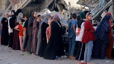 Palestinian women line up to buy fresh bread next to destroyed buildings at the Nuseirat refugee camp in the central Gaza Strip on November 4, 2023. (AFP) Palestinian women line up to buy fresh bread next to destroyed buildings at the Nuseirat refugee camp in the central Gaza Strip on November 4, 2023. (AFP)
