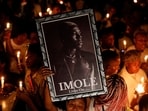 A woman holds a photograph of late Nigerian singer Mohbad, during a candlelight procession to press authorities to investigate his death, in Abuja, Nigeria.