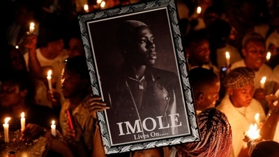 A woman holds a photograph of late Nigerian singer Mohbad, during a candlelight procession to press authorities to investigate his death, in Abuja, Nigeria. (REUTERS)