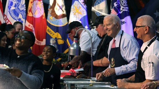 NOVEMBER 19: U.S. President Joe Biden alongside Chef Robert Irvine (R) serves service members and military families from the USS Dwight D. Eisenhower and the USS Gerald R. Ford during a Friendsgiving dinner event at the Norfolk Naval Station on November 19, 2023 in Norfolk, Virginia. Co-hosted by the USO and Robert Irvine Foundation, President Biden and the first lady host Naval families prior to the Thanksgiving holiday. (Getty Images via AFP)