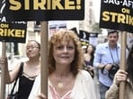 Susan Sarandon pick up a sign for the strike. Outside the Warner Bros. studios in Burbank, California, throngs of protesters chanted: “Fists up, curtains down, LA is a union town.” Food trucks flanking organizers' tents served churros, boba tea and cold lemonade to protesters baking in the midday heat that reached 98 degrees Fahrenheit (36.7 Celsius).&nbsp;