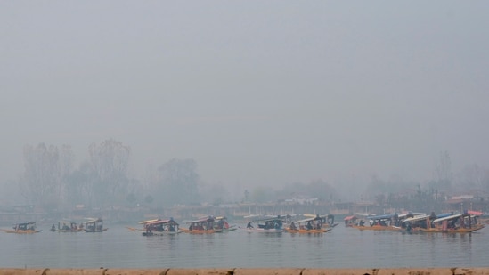 Boatmen row their 'shikaras' carrying tourists on Dal Lake amid dense fog, in Srinagar.(PTI)