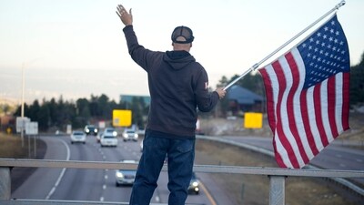 A man waves an American flag at motorists as they move westbound along Interstate 70 during the Thanksgiving holiday travel rush late Wednesday, Nov. 22, 2023, near Evergreen, Colo. (AP Photo/David Zalubowski) (AP) A man waves an American flag at motorists as they move westbound along Interstate 70 during the Thanksgiving holiday travel rush late Wednesday, Nov. 22, 2023, near Evergreen, Colo. (AP Photo/David Zalubowski) (AP)