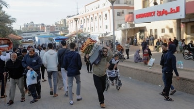 A displaced Palestinian man, who fled his house due to Israeli strikes, carries his belongings as he makes his way back to his home, during a temporary truce between Hamas and Israel in the southern Gaza Strip. (REUTERS)