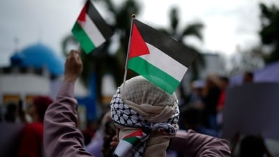 A Filipino Muslim holds Palestinian flags during a demonstration in support of the Palestinian people and calling for a ceasefire in Gaza outside the Blue Mosque in Taguig, Philippines on Friday, Nov. 24, 2023. (AP Photo/Aaron Favila) (AP)