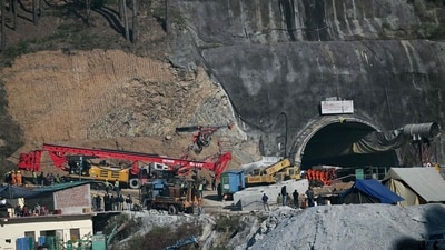 Rescue personnel move a digging machine during rescue operation for workers trapped in the Silkyara under construction road tunnel. (AFP) Rescue personnel move a digging machine during rescue operation for workers trapped in the Silkyara under construction road tunnel. (AFP)