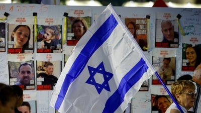 A woman holding an Israeli flag walks past placards as people await news of hostages expected to be released by Hamas, amid a hostages-prisoners swap deal between Hamas and Israel, in Tel Aviv, Israel, November 25, 2023. REUTERS/Alexander Ermochenko (REUTERS)