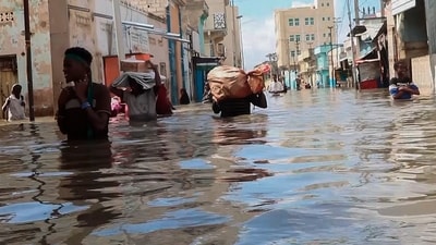 In this image made from video, men walk through floodwaters on a street in the town of Beledweyne, in Somalia. (AP)