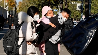 A man carries a child as they leave a children's hospital in Beijing, Friday, Nov. 24, 2023. (AP)