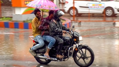 Commuter ride past during a rain, in Surat on Sunday. (ANI) Commuter ride past during a rain, in Surat on Sunday. (ANI)