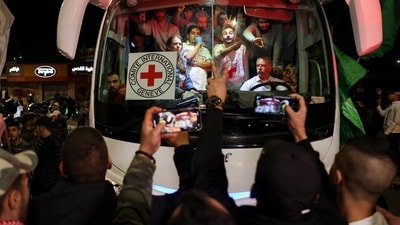 A bus transporting Red Cross staff and Palestinians prisoners released from Israeli jails in exchange for hostages released by Hamas from the Gaza Strip, drives through supporters holding flags in Ramallah in the occupied West Bank early on November 26, 2023. (AFP)