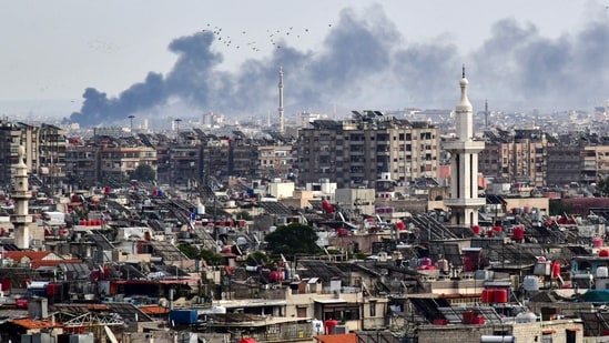 Smoke billows above buildings after an Israeli strike on the outskirts of Damascus (AFP)
