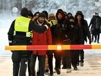 A Finnish Border Guard speaks to migrants at the international border crossing at Salla, northern Finland, on November 23, 2023. 