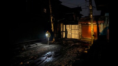 A man uses a cell phone torch and walks on a road during a power outage on a cold evening in Srinagar on Monday. (AP)