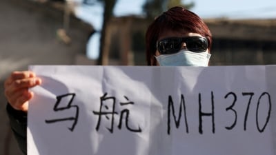 Hu Xiufang, 72, who lost her son, daughter-in-law and granddaughter, holds a sign as she speaks to the media. (Reuters)