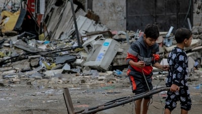Israel-Hamas War: Palestinian children walk amid debris of buildings hit in Israeli strikes, near Al-Zawiya market in Gaza City. (AFP)
