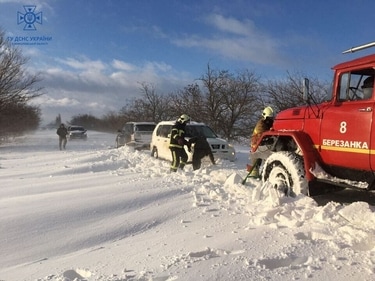 Emergency workers release cars which are stuck in snow during a heavy snow storm in Mykolaiv region in Ukraine on November 27. (Reuters)
