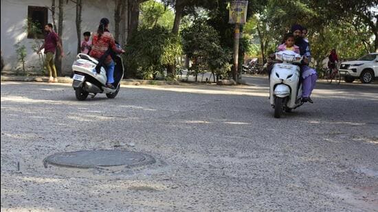 Commuters navigating through the potholed road in Bhai Randhir Singh Nagar in Ludhiana. (Manish/HT)