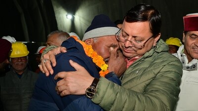 Chief minister Pushkar Singh Dhami with one of the rescued workers. (HT)