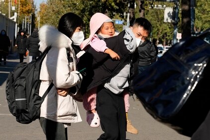 A man carries a child as they leave a children's hospital in Beijing on November 24, (AP) A man carries a child as they leave a children's hospital in Beijing on November 24, (AP)