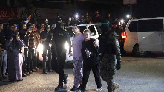 Hamas and Islamic fighters accompany newly released Israeli hostages, held since the Hamas' October 7 attacks, before handing them over to the Red Cross in Rafah. (AFP)