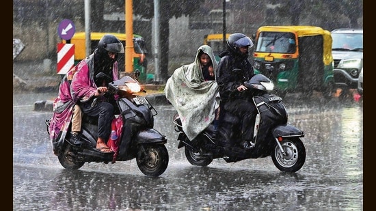 Commuters caught in the rain in Chandigarh on Thursday. (Keshav Singh/HT)