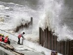 High tidal waves lash the shore as construction workers stand nearby. High tidal waves lash the shore as construction workers stand nearby.