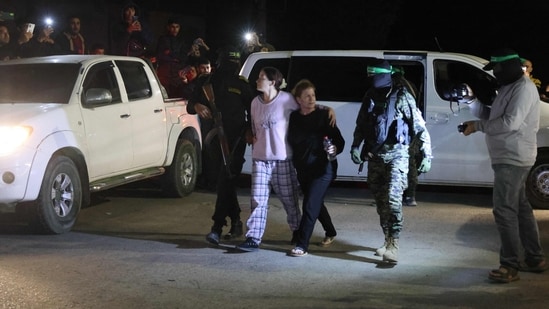 Hamas and Islamic Jihad fighters accompany newly released hostages before handing them over to the Red Cross in Rafah, in the southern Gaza Strip. (AFP)