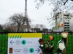 This photograph taken on December 3, 2023 shows flowers where a tourist was stabbed to death on the eve, near the Eiffel Tower (background), in Paris. (Photo by Dimitar DILKOFF / AFP)