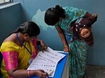 A woman checks for her name before casting her vote at a polling station during the Telangana state assembly elections.(AP)