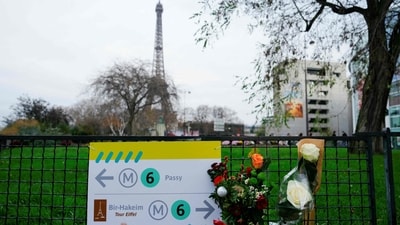 This photograph taken on December 3, 2023 shows flowers where a tourist was stabbed to death on the eve, near the Eiffel Tower (background), in Paris. (Photo by Dimitar DILKOFF / AFP) (AFP)