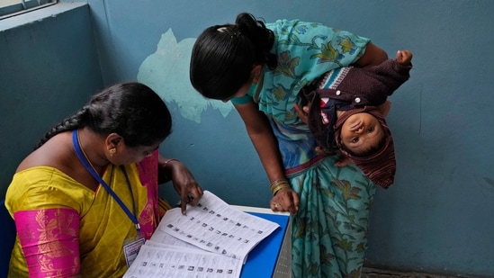 A woman checks for her name before casting her vote at a polling station during the Telangana state assembly elections. A woman checks for her name before casting her vote at a polling station during the Telangana state assembly elections.