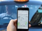  A photo illustration shows the Uber app and a black cab in London, Britain.