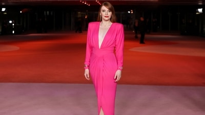 Bryce Dallas chose a Barbie Pink dress featuring a plunging neckline and asymmetric silhouette for the Academy Museum Gala red carpet. She styled the look with metal gold accessories, red pumps, matching lip shade, side-parted open locks, winged eyeliner, and blushed glowing base.&nbsp; (REUTERS)