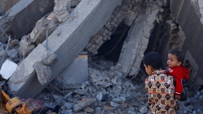 Israel-Hamas War: A Palestinian boy carrying a baby stands at a site of Israeli strikes, amid the ongoing conflict between Israel and Hamas. (Reuters)