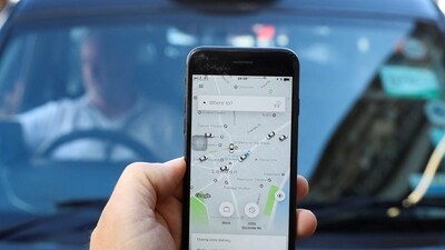 A photo illustration shows the Uber app and a black cab in London, Britain. (REUTERS)