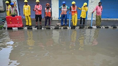 Construction workers stand on footpath as road gets waterlogged due to heavy rains in Chennai. (AFP) Construction workers stand on footpath as road gets waterlogged due to heavy rains in Chennai. (AFP)