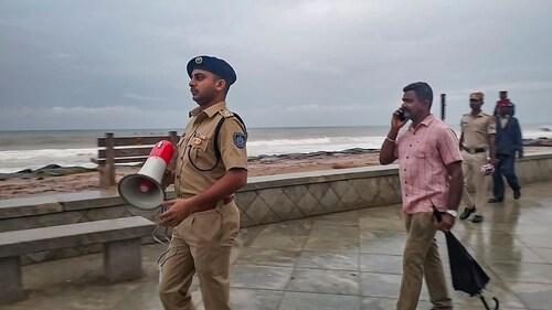 Policemen patrol on a pathway along the seashore ahead of the landfall of Cyclone Michaung in Puducherry on Sunday. (PTI) Policemen patrol on a pathway along the seashore ahead of the landfall of Cyclone Michaung in Puducherry on Sunday. (PTI)