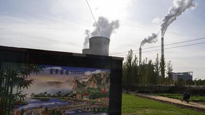 A resident rides past the Guohua Power Station in Dingzhou, Baoding in the northern China’s Hebei province. (AP)