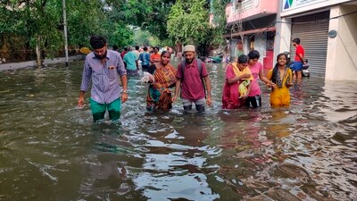 People wade through a flooded road after heavy rainfall owing to Cyclone Michaung, in Chennai. (PTI) People wade through a flooded road after heavy rainfall owing to Cyclone Michaung, in Chennai. (PTI)