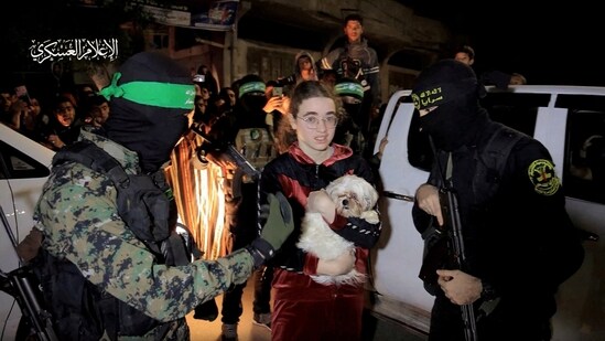 A hostage who was abducted by Hamas gunmen during the October 7 attack on Israel, while she and others are handed over by Hamas militants to members of the International Committee of the Red Cross. (Reuters)