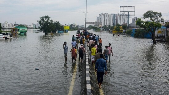 People walk by the median of a flooded road following heavy rains along the Bay of Bengal coast in Chennai, India, Tuesday, Dec.5, 2023. (AP)