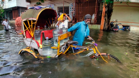 A rickshaw puller wades through flooded road after heavy rainfall owing to Cyclone Michaung in Chennai.(PTI)