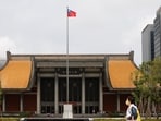 People walk near a fluttering Taiwanese flag outside the Sun Yat-Sen Memorial Hall in Taipei, Taiwan. 
